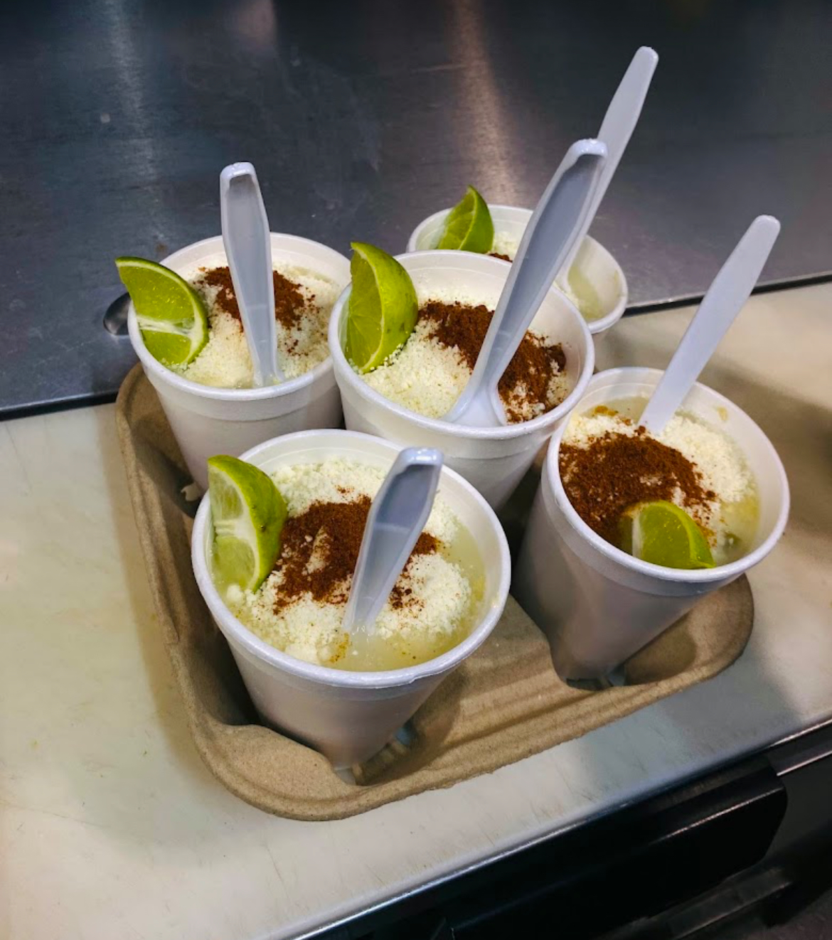 Cups of esquites topped with cheese, chile and lime